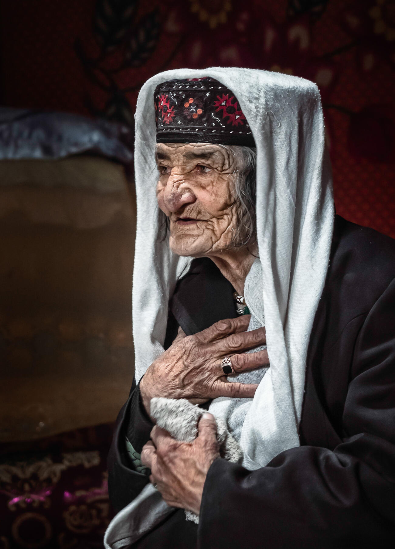 frontier-discovery-project-elderly-woman.jpg Old lady signs with her hand to her chest to guest in her colorful home
